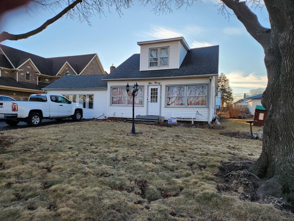 view of front of home featuring a shingled roof and a front yard