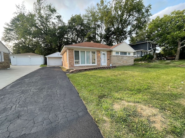 view of front of house with a front yard, a detached garage, an outdoor structure, and brick siding