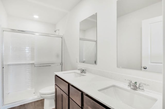 bathroom with a stall shower, a sink, toilet, and double vanity