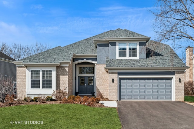 view of front of house with a front lawn, driveway, a shingled roof, brick siding, and a chimney