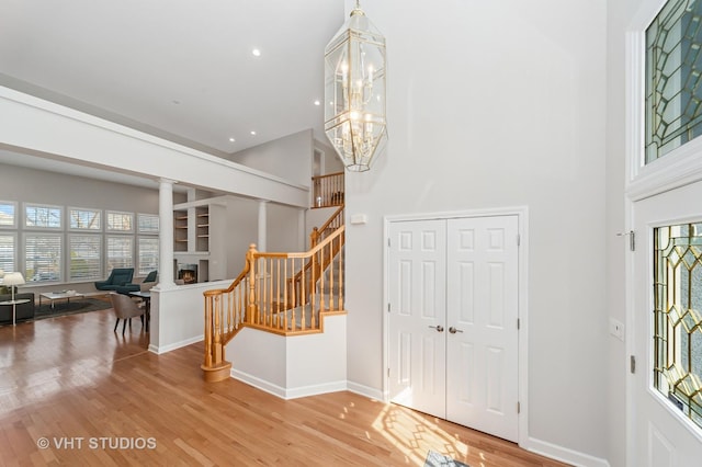 entrance foyer with wood finished floors, baseboards, a high ceiling, stairs, and a notable chandelier