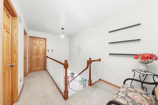 hallway with baseboards, light carpet, and an upstairs landing