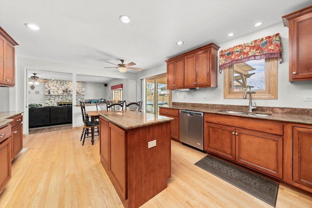 kitchen with a sink, light wood-style flooring, a kitchen breakfast bar, and dishwasher