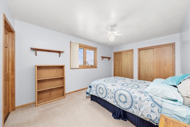 carpeted bedroom with multiple closets, ceiling fan, and baseboards