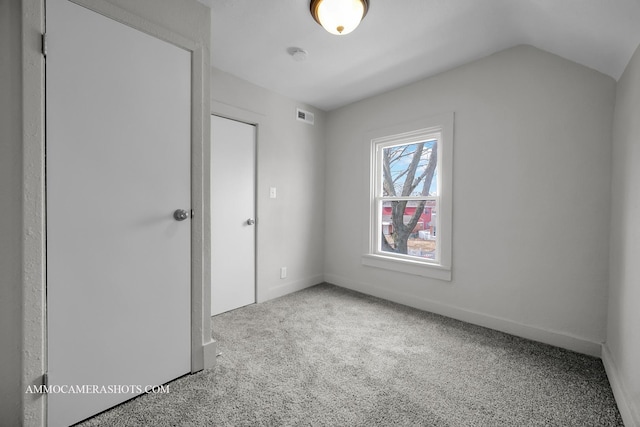 unfurnished bedroom featuring lofted ceiling, baseboards, visible vents, and carpet flooring