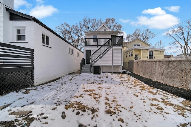 snow covered house with stairs and fence