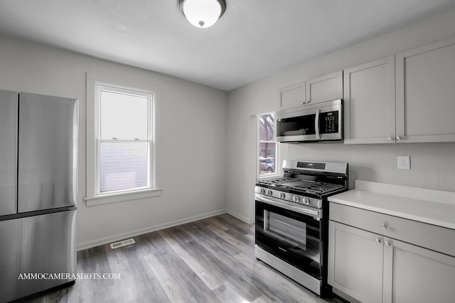 kitchen featuring light wood finished floors, visible vents, baseboards, appliances with stainless steel finishes, and light countertops