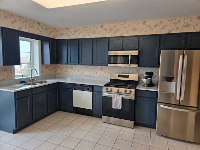 kitchen featuring a sink, stainless steel appliances, light countertops, and wallpapered walls