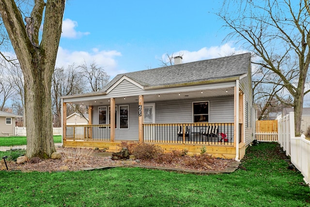 view of front of house featuring a porch, a chimney, a shingled roof, and fence