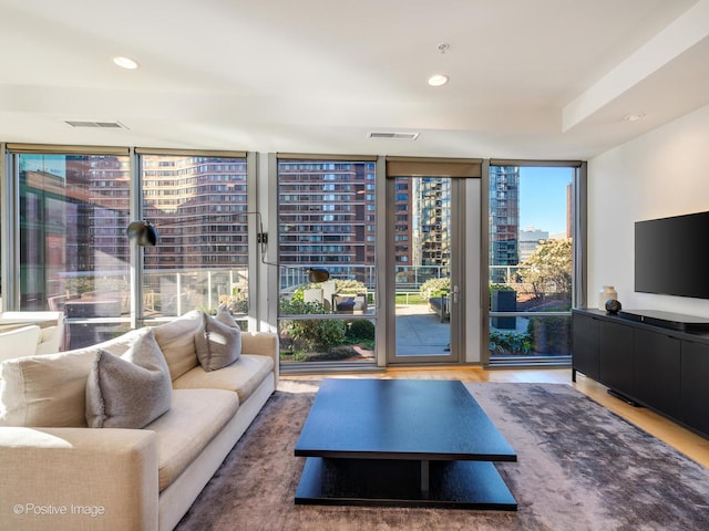 living room featuring a wall of windows, recessed lighting, visible vents, and wood finished floors