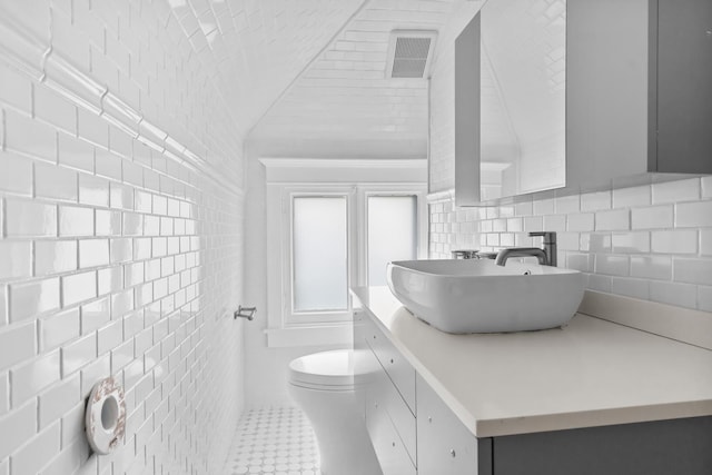 714 Sheridan Rd, Evanston, IL 60202 - bathroom featuring tile walls, vaulted ceiling, toilet, and vanity