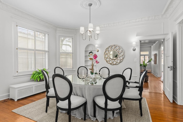 714 Sheridan Rd, Evanston, IL 60202 - dining space with wood finished floors, a chandelier, baseboards, and crown molding