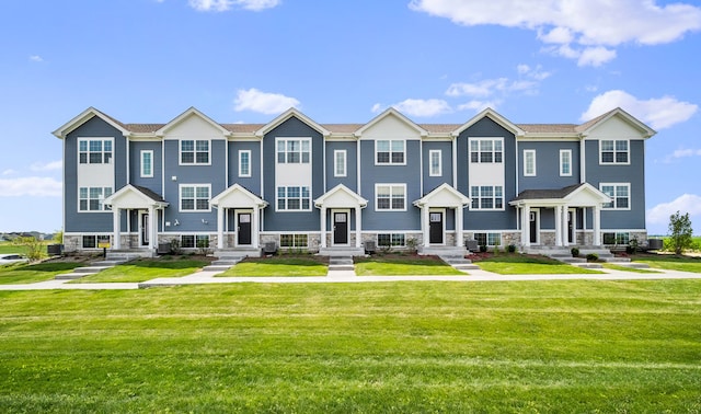 view of property featuring stone siding, a residential view, a front lawn, and cooling unit