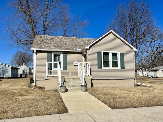 bungalow with roof with shingles and a front yard