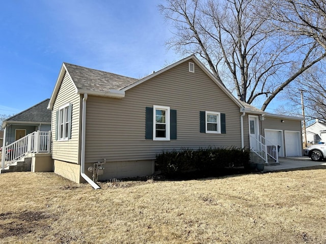 view of side of home featuring a garage, a yard, and a shingled roof