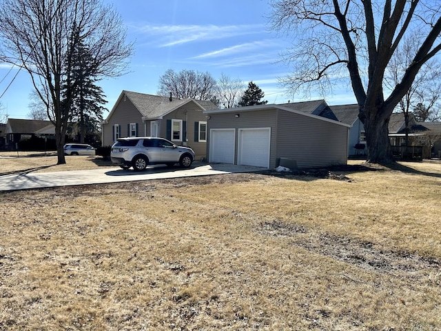 exterior space featuring a garage, concrete driveway, and a front lawn