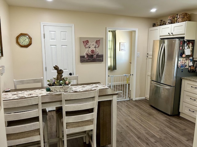 kitchen featuring dark wood finished floors, light countertops, freestanding refrigerator, white cabinets, and baseboards