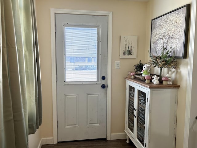 doorway featuring baseboards and dark wood-type flooring