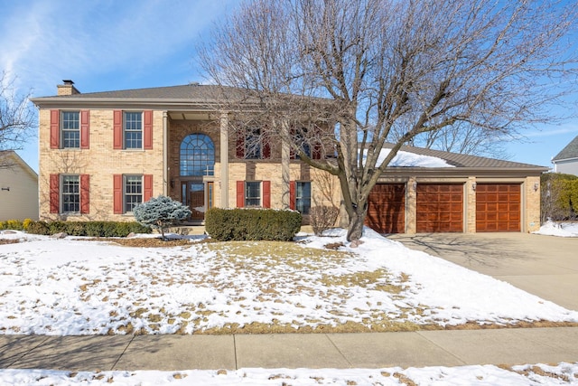 view of front of house with concrete driveway, brick siding, a chimney, and an attached garage