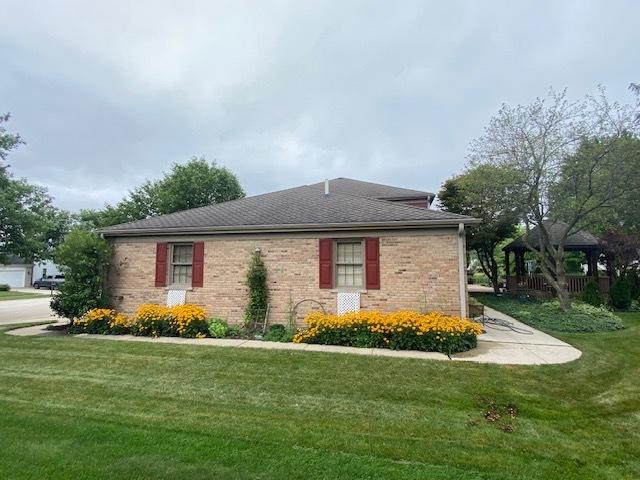 view of side of home featuring a gazebo, brick siding, and a lawn
