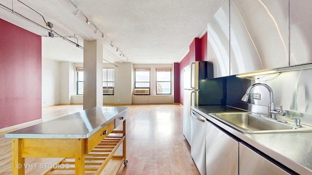 kitchen featuring stainless steel counters, light wood-style floors, cooling unit, a sink, and dishwasher