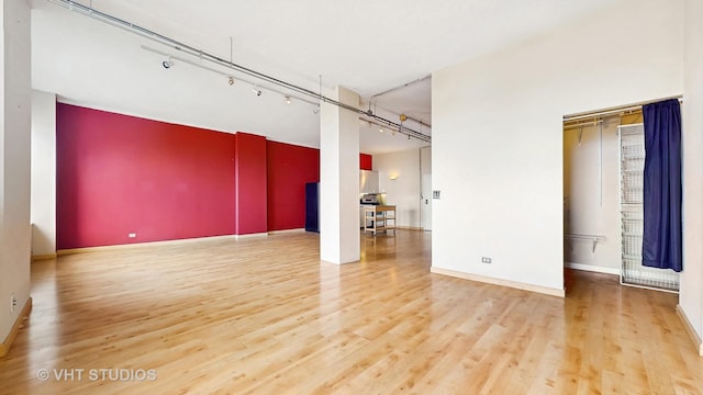 empty room featuring baseboards, wood finished floors, and rail lighting