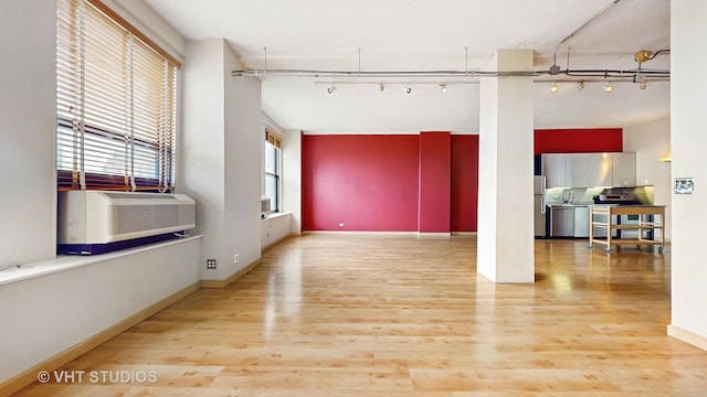 unfurnished living room with rail lighting, wood finished floors, and cooling unit