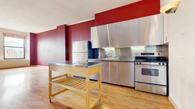 kitchen with stainless steel counters, baseboards, a sink, and stainless steel appliances