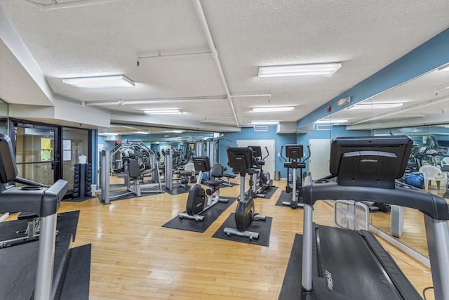 exercise room with visible vents, a textured ceiling, and wood finished floors