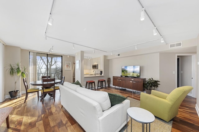 living room with rail lighting, visible vents, and dark wood finished floors