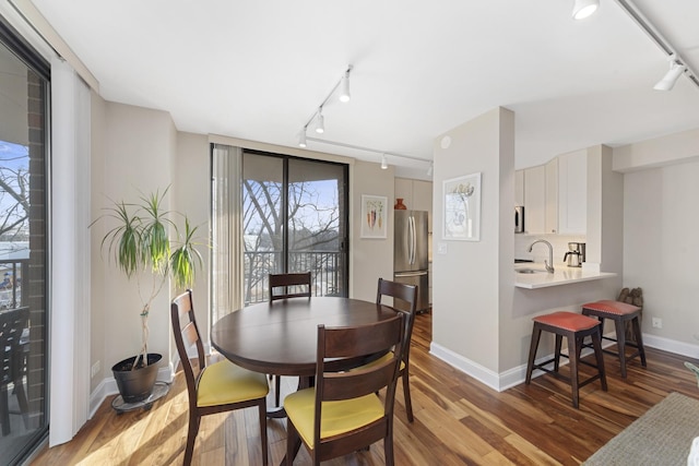 dining room featuring track lighting, baseboards, and wood finished floors