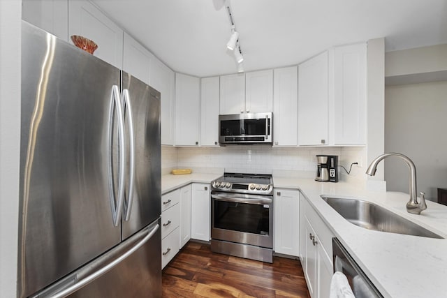 kitchen with dark wood-style flooring, a sink, white cabinets, appliances with stainless steel finishes, and decorative backsplash