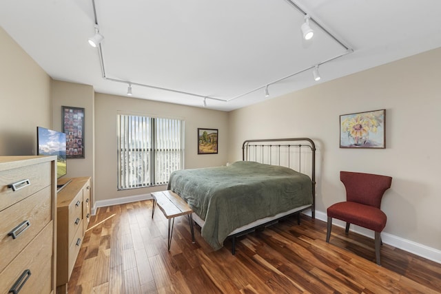 bedroom with wood finished floors, rail lighting, and baseboards