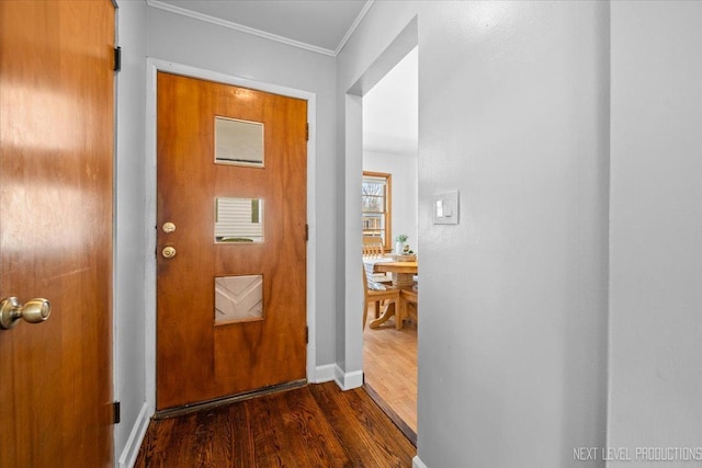 doorway to outside with ornamental molding, dark wood-style flooring, and baseboards