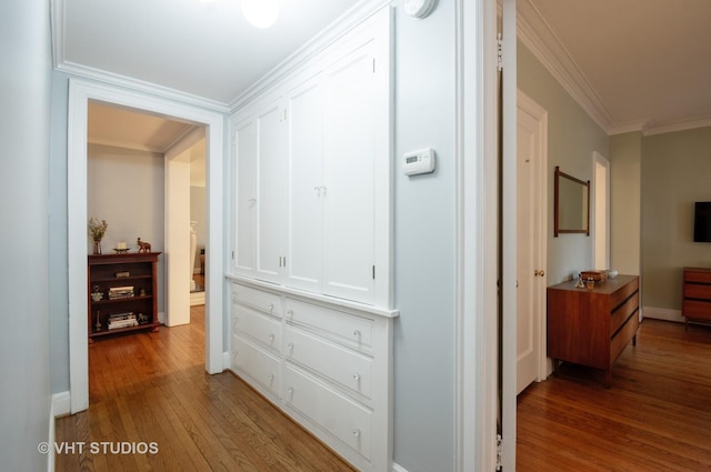 hall with ornamental molding and wood finished floors