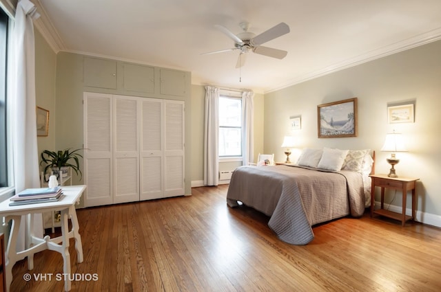 bedroom with ceiling fan, wood finished floors, baseboards, ornamental molding, and a closet