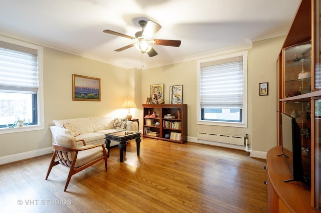 sitting room with ornamental molding, baseboard heating, light wood-type flooring, and a ceiling fan