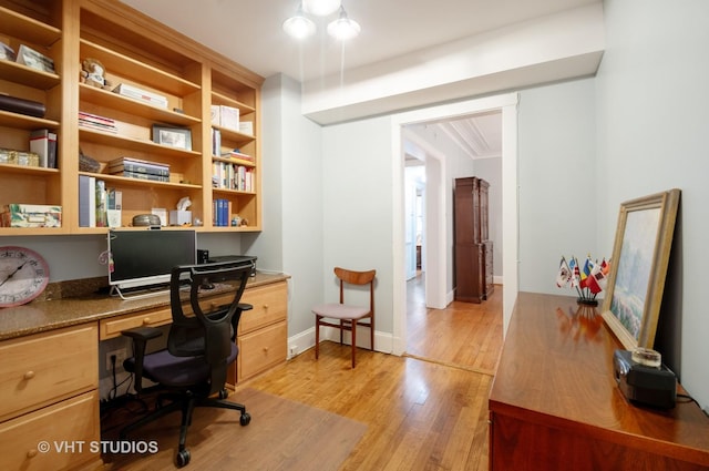 office space featuring light wood-type flooring, baseboards, and built in study area