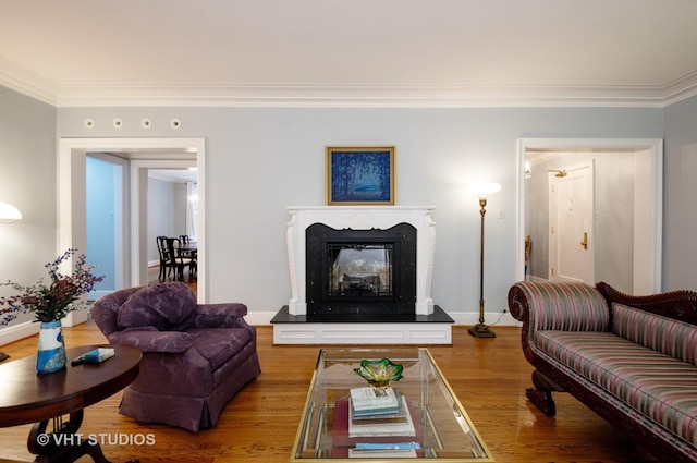 living room featuring crown molding, baseboards, wood finished floors, and a glass covered fireplace