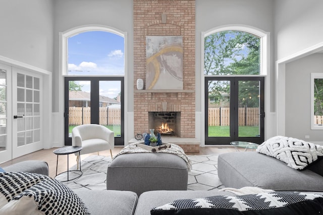 living room with a fireplace, a high ceiling, a wealth of natural light, and french doors