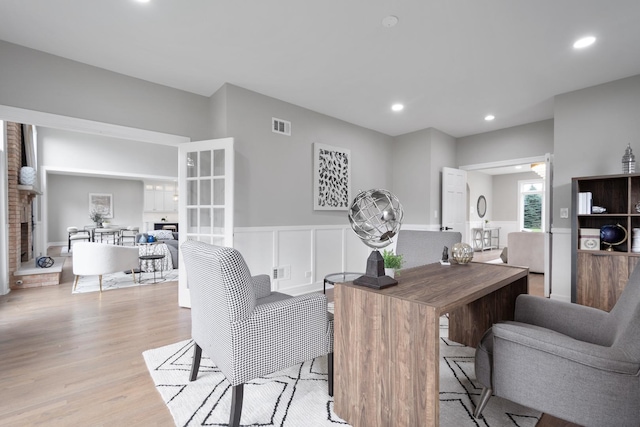 dining space featuring recessed lighting, visible vents, wainscoting, a brick fireplace, and light wood finished floors