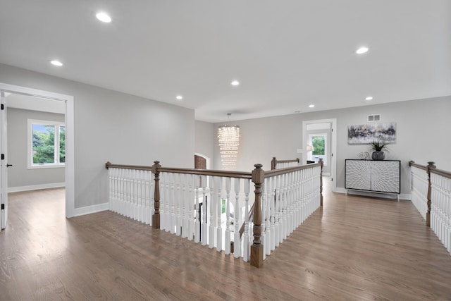 hallway featuring visible vents, wood finished floors, an upstairs landing, and recessed lighting