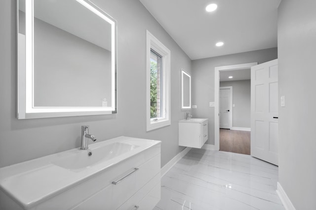 bathroom with a sink, recessed lighting, two vanities, and baseboards