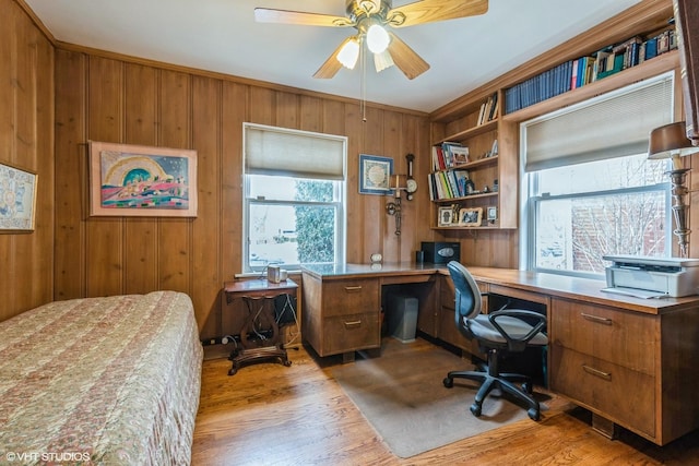 office space with wooden walls, light wood-style flooring, and a ceiling fan