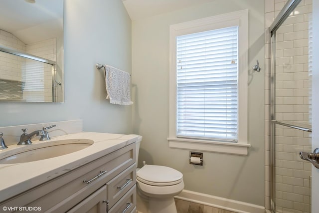 full bathroom with toilet, wood finished floors, vanity, baseboards, and a stall shower