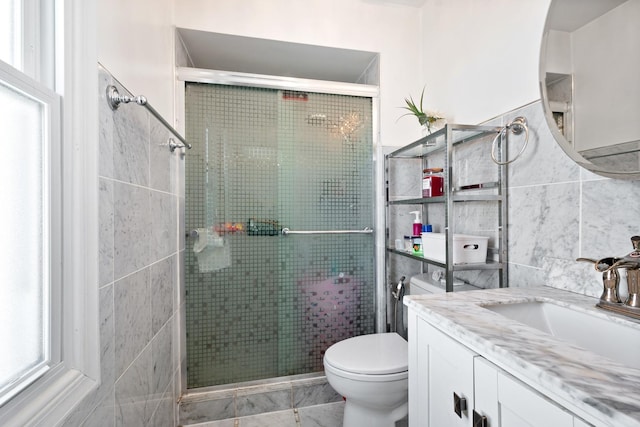 bathroom featuring toilet, a stall shower, tile walls, and vanity