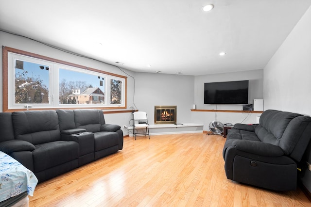 living area with recessed lighting, wood finished floors, and a glass covered fireplace