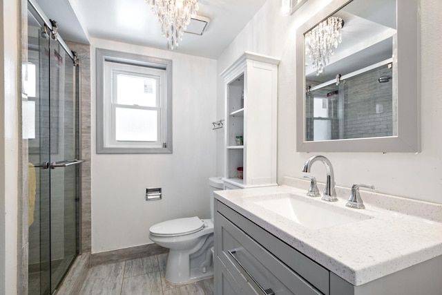 bathroom featuring toilet, a stall shower, vanity, a chandelier, and baseboards