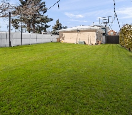 view of yard with a fenced backyard and central air condition unit