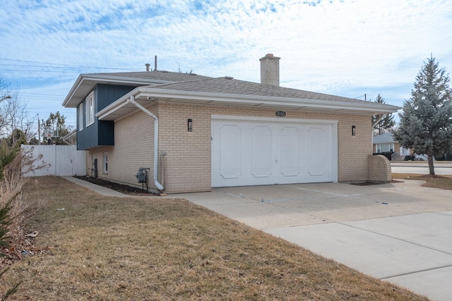 view of side of property with driveway, a yard, a chimney, and brick siding